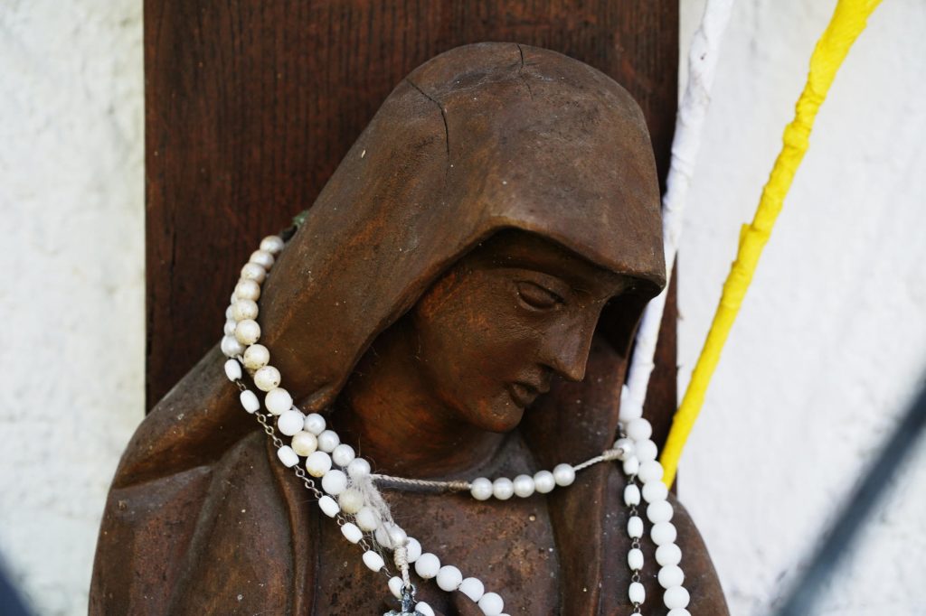 Frau unter dem Kreuz mit Rosenkranz